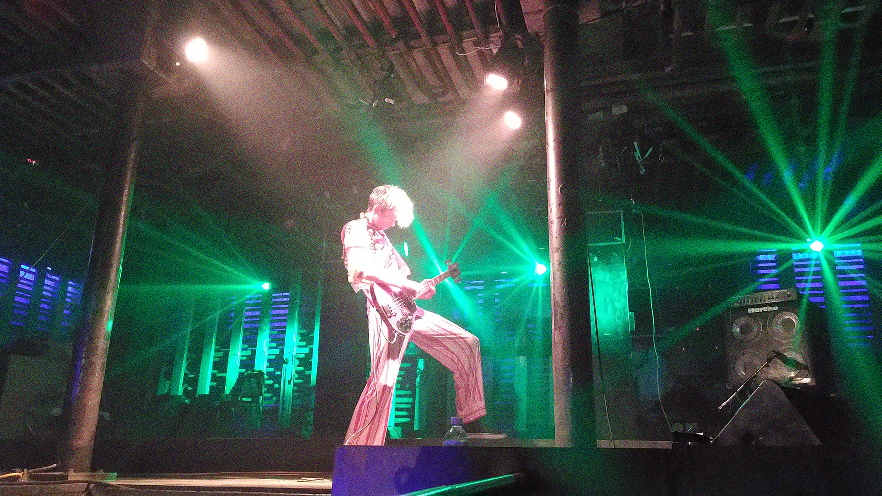 Konzert von Siksa 2022. Ein Mensch steht in grünem Licht auf der Bühne und spielt Gitarre.
