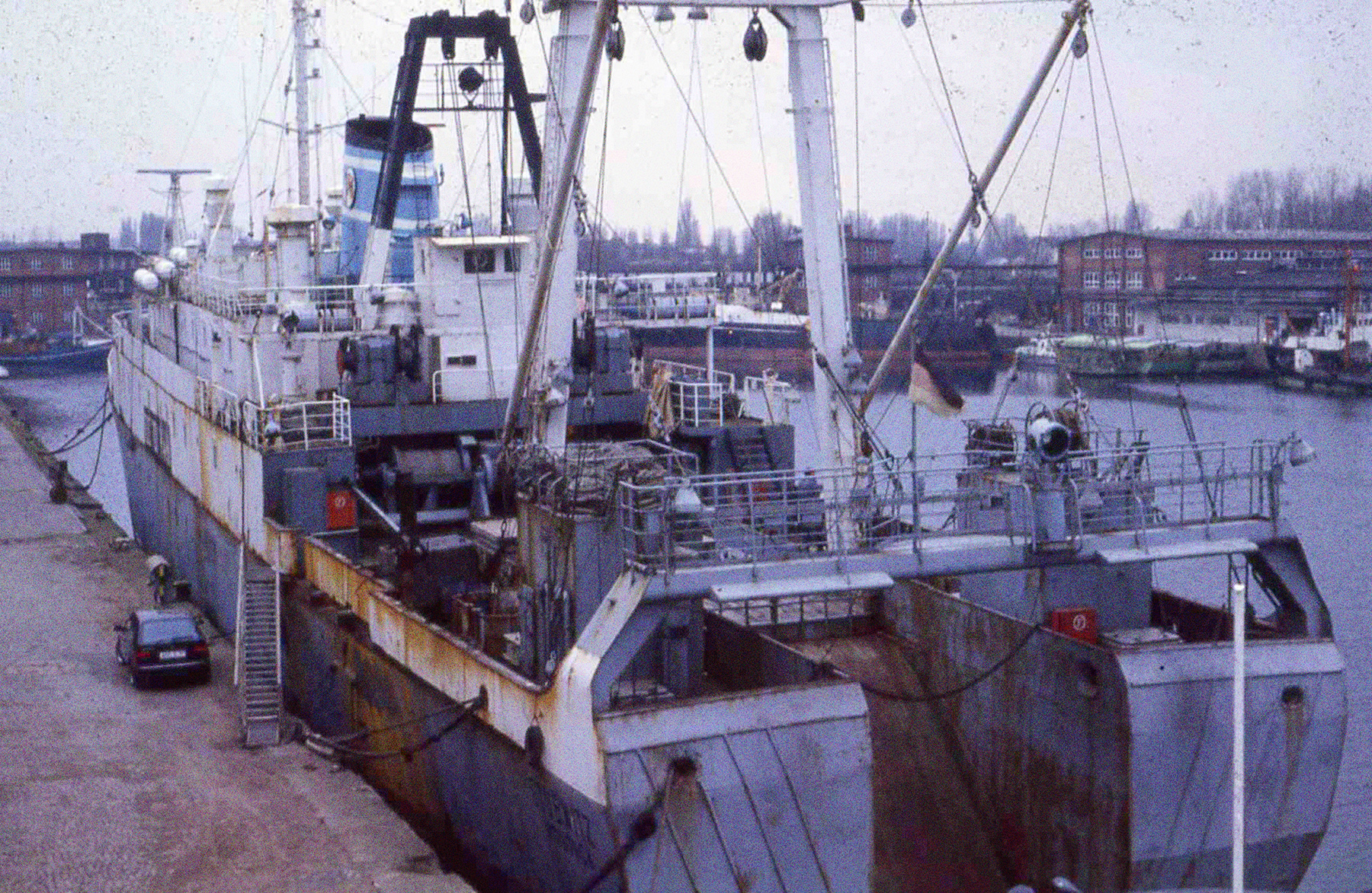 Die Stubnitz in Rostock kurz vor ihrer geplanten Verschrottung 1992, fotografiert von schräg hinten. Links neben dem Schiff steht ein kleines Auto.