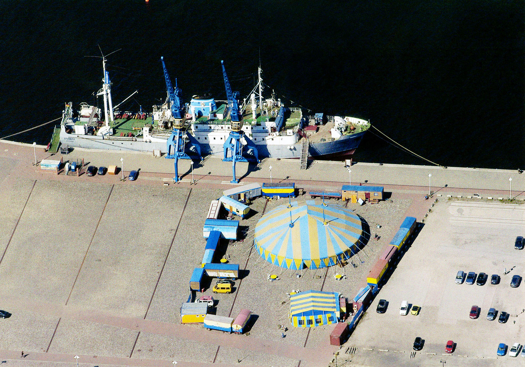 Die Stubnitz liegt im Rostocker Hafen 2010. Foto aus der Vogelperspektive. Vor dem Schiff an Land ist ein Zirkus aufgebaut.