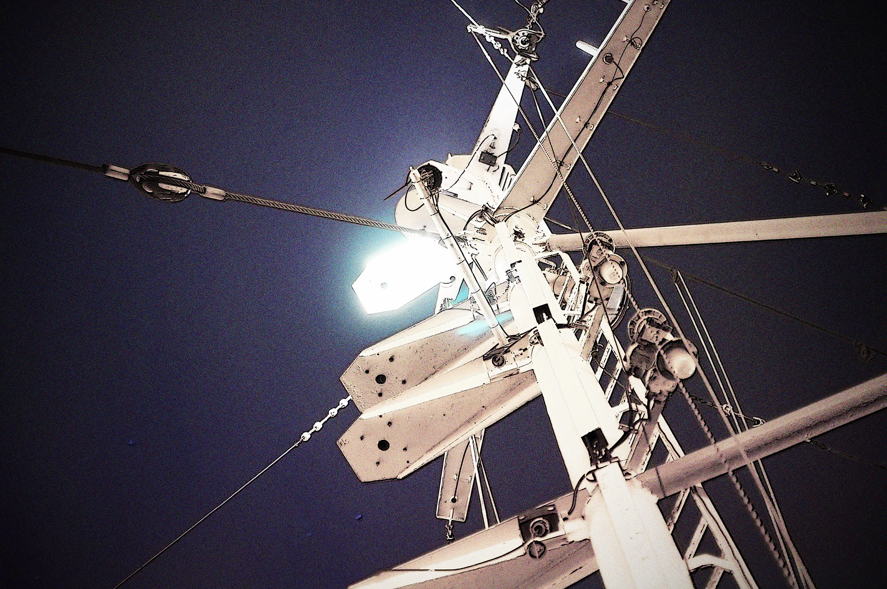 Der weiße Funkmast vor einem dunkelblauen Nachthimmel. Am Mast leuchtet eine helle, weiße Lampe.