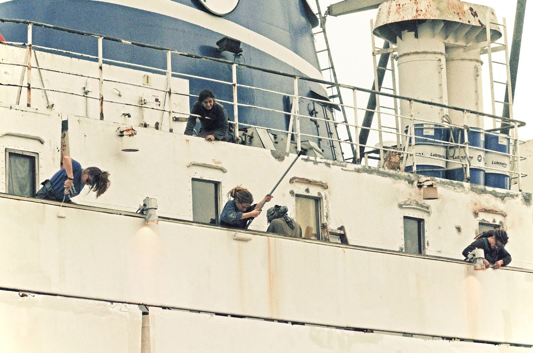 Mal- und Lackierarbeiten an der Außenhaut 2013. Mehrere Menschen lehnen sich über die Reling und lackieren das Schiff von Außen.