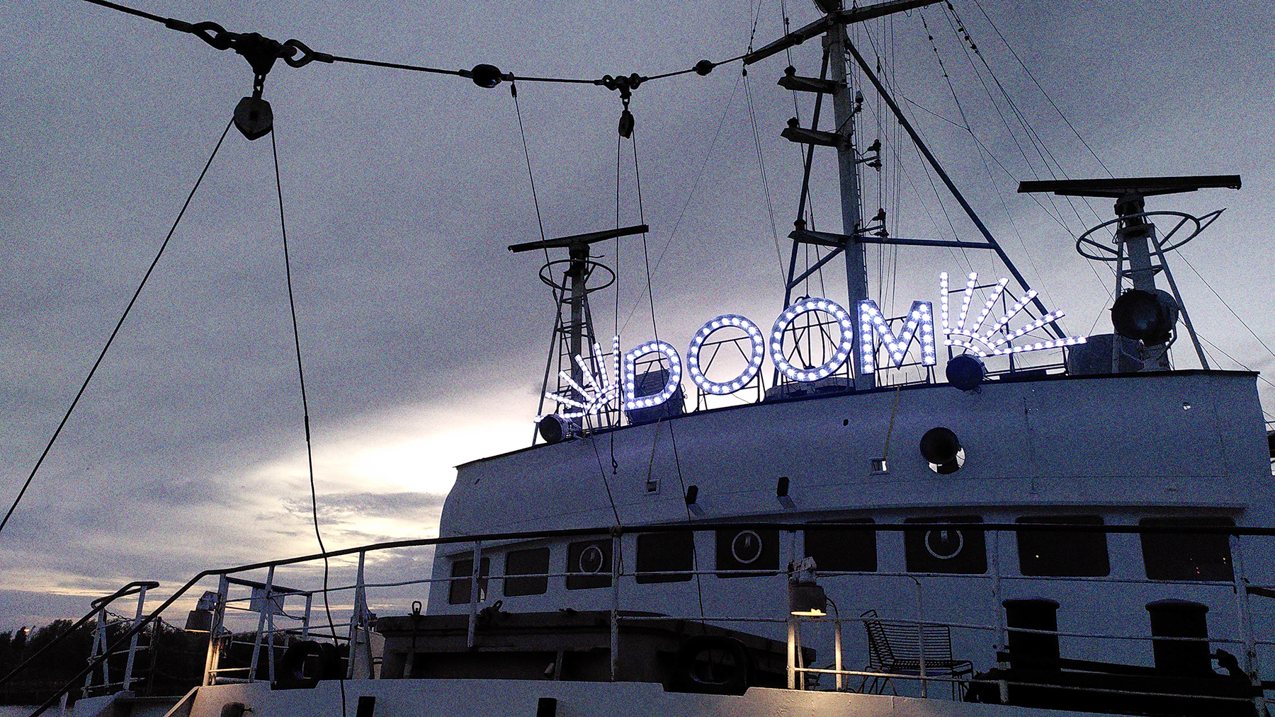 Die Ausstellung No Escape Room. Die Stubnitz in Nahaufnahme. Über der Brücke ist in Leuchtbuchstaben das Wort “Doom” angebracht.