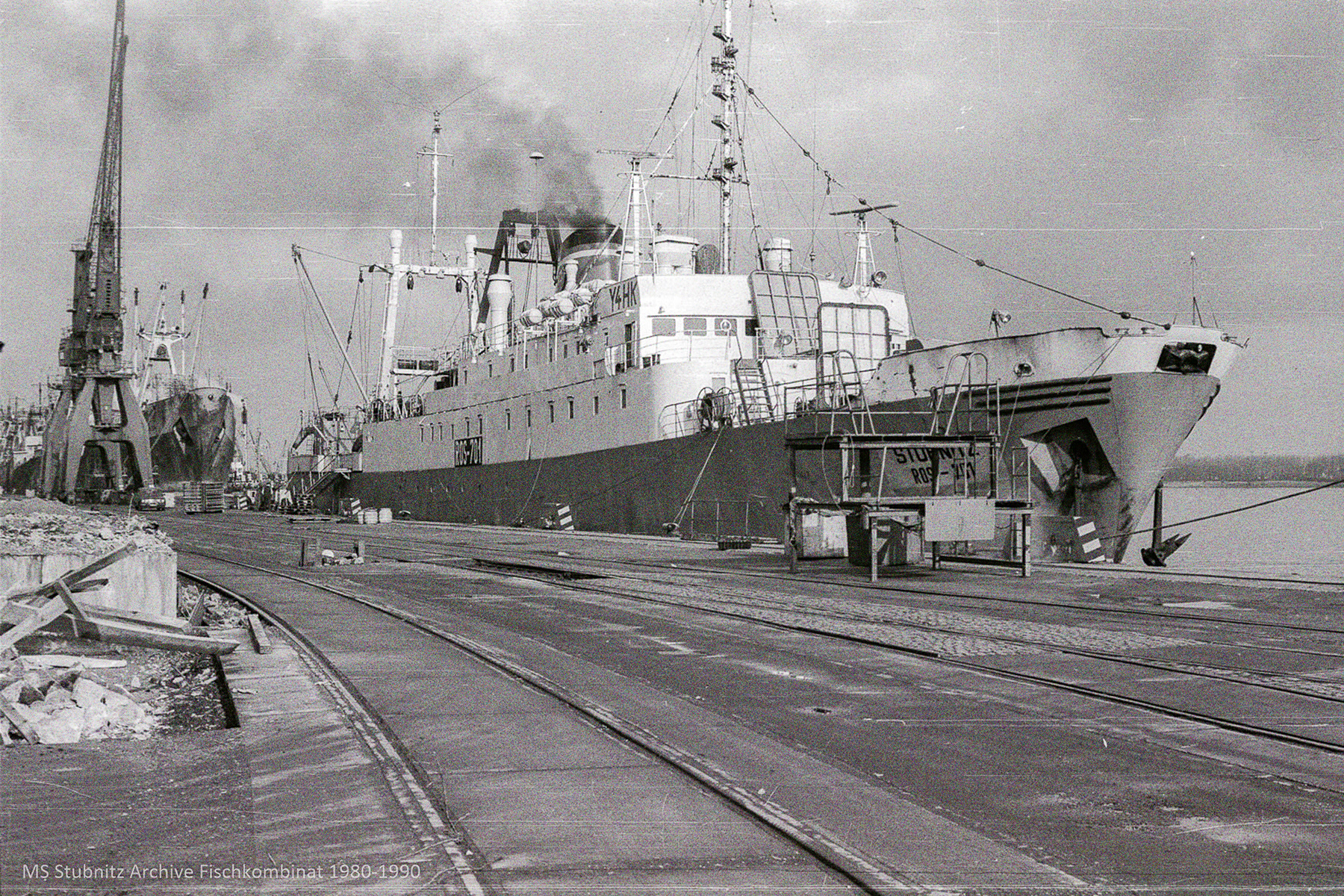 Die Stubnitz im Rostocker Hafen beim Verladen. Im Hintergrund ein anderes Schiff und ein Krahn.