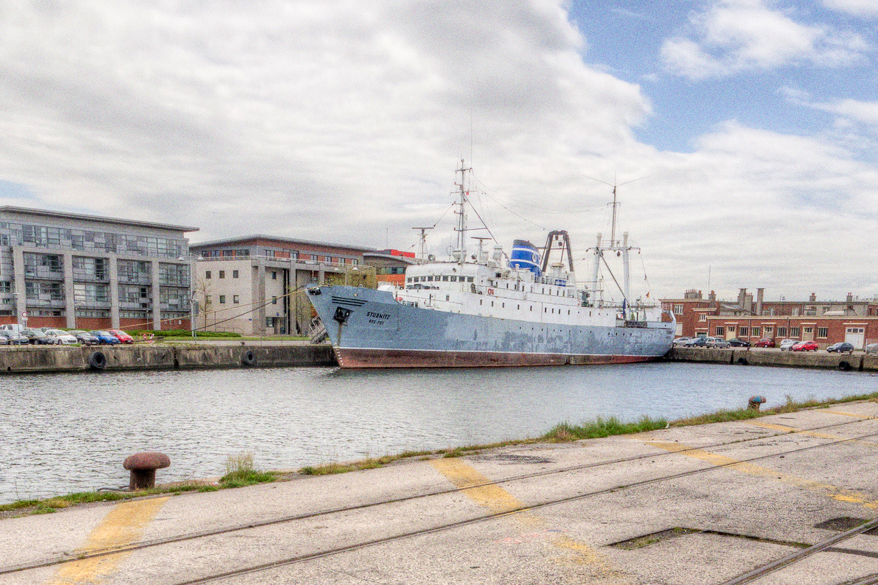 Die Stubnitz in Dunkerque 2013. Im Vordergrund die gegenüberliegende Uferseite mit Schienen. Im Hintergrund Gebäude.