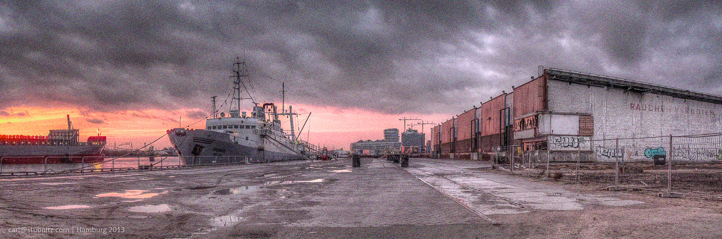 Die Stubnitz im Hamburger Baakenhafen 2014. Auf der rechten Seite die Hallen des ehemaligen Afrikaterminals. Links Hafengebäude, andere Schiffe und Sonnenuntergang