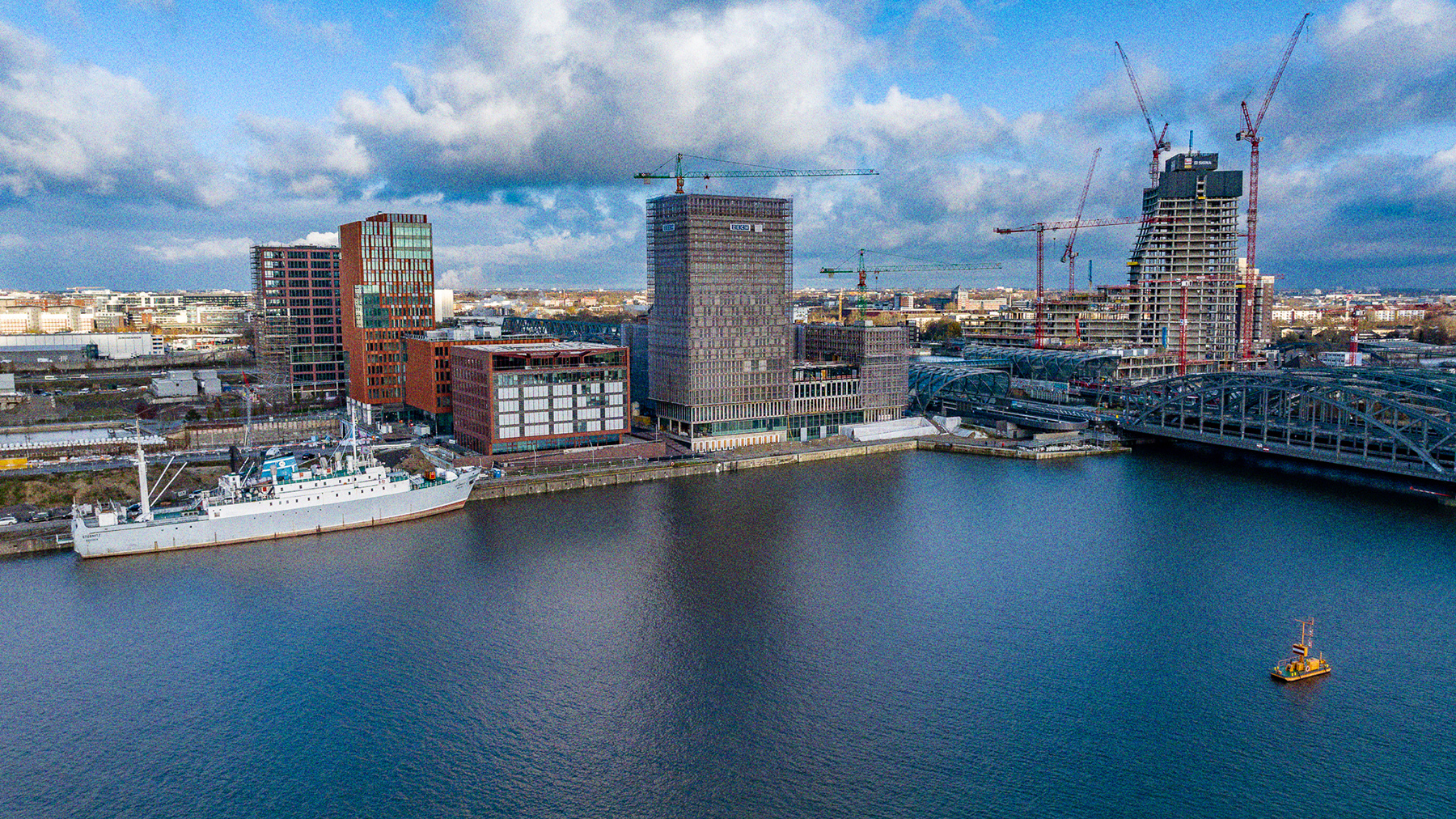 Die Stubnitz an ihrem aktuellen Liegeplatz an den Elbbrücken. Aus der Vogelperspektive fotografiert. Im Hintegrund die Stadtteile HafenCity und Rothenburgsort. Auf der rechten Seite die Elbbrücken und der U- und S-Bahnhof Elbbrücken. Im Vordergrund Wasser.