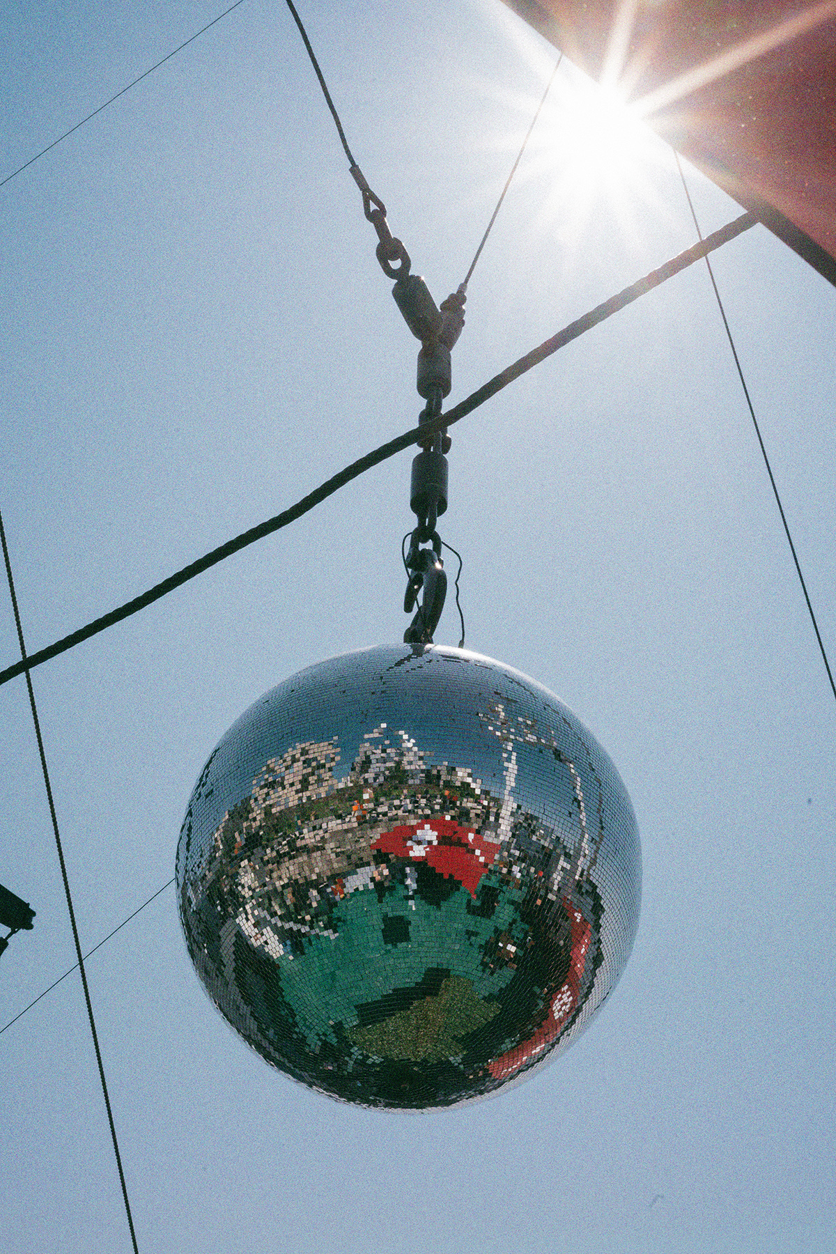 Eine große Discokugel hängt auf dem Achterdeck. Im Hintergrund blauer Himmel und Sonnenstrahlen.